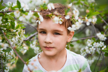 Child boy outdoors in a beautiful spring garden. Kid with flower cherry tree garden. Summertime
