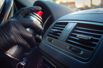 Cleaning the climate system and air conditioner of a car from a coronovirus and a pandemic with a disinfectant fluid. Hands in rubber protective gloves wipe the car