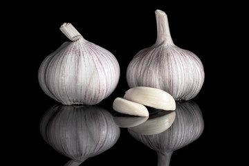 two garlic head and two garlic slices on a black background