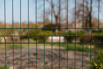 Steel grill fence with blurred wire background