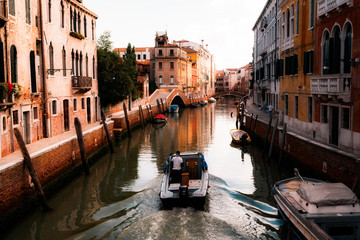 Fototapeta na wymiar Narrow medieval rustic canal as the sun is setting in Venice