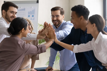 Diverse workers coach giving high five at company meeting. Happy multiracial colleagues with indian and black managers celebrating achievement, corporate success of teamwork, team building activity.