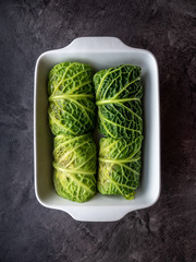 Kale leaves stuffed with meatballs in white ceramic baking dish.