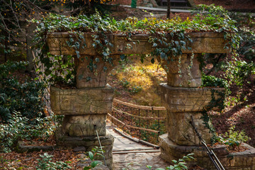 Naklejka premium Stone arch, entrance to a suspended wooden bridge.