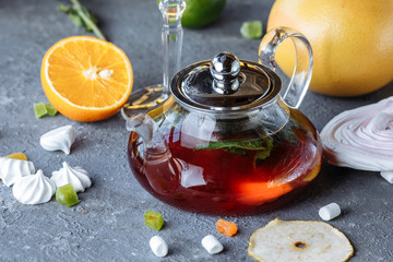 Fruit tea with mint, oranges and cranberries on a decorative background. Hot winter drinks. A teapot of hot tea