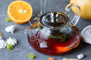 Obraz na płótnie Canvas Fruit tea with mint, oranges and cranberries on a decorative background. Hot winter drinks. A teapot of hot tea