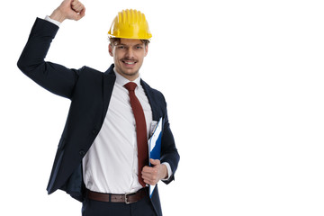 Cheerful businessman holding clipboard celebrating while wearing construction helmet