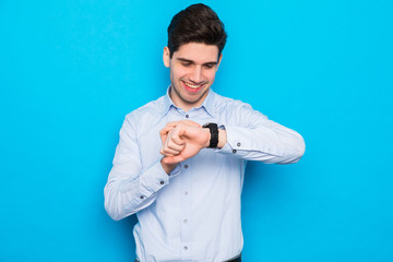 Young handsome man watch the hand watch over isolated blue background