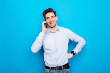 Naklejka premium Young man talking on phone against blue background