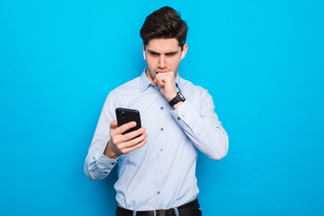 young man is pondering his decision on the phone on blue background