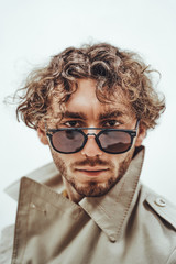 Cool and assertive young man with curly hair posing on the white background of the studio looking right on camera