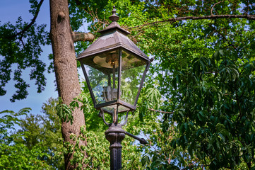 Historic and still functional street lamp that is powered by gas and stands in a Berlin park.