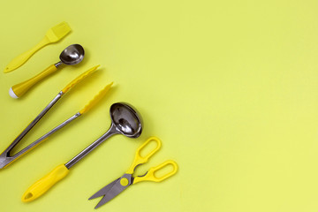 kitchen ladle accessories, scissors, tongs, brush, yellow ice cream spoon on a yellow background