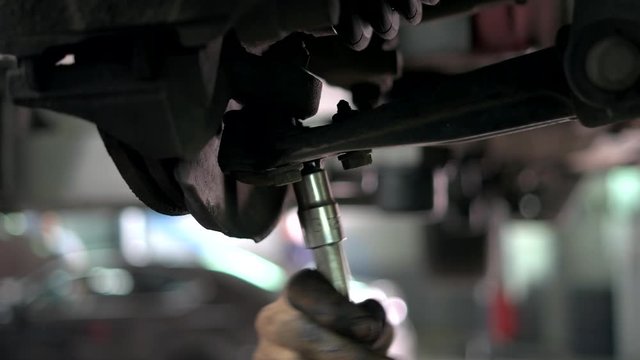 Close up unscrewing car nuts. Auto mechanic with dirty hands uninstalling som car detail.