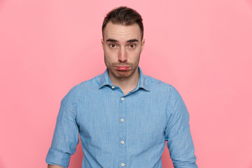 casual man is upset, standing and wearing a blue shirt