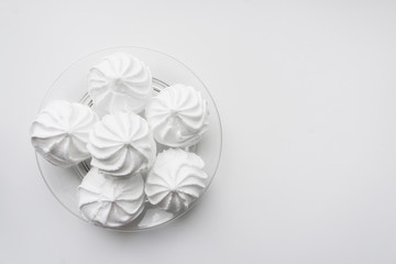 Fototapeta na wymiar White zephyr in white plate on a white background with copy space. Baking for a bakery, coffee shop or sweet shop. French vanilla meringue cookies. Invitation on coffee or tea, gift for kids or girl