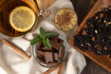 Fragrant flower tea with lemon and cinnamon, a plate with sweets: chocolate, honey and mint, and...