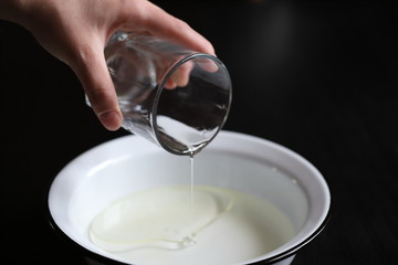 pour vegetable olive oil from a glass container of a glass into a bowl of water to make pizza dough and pies, cook at home in the kitchen for the family with love