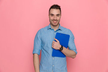 casual man holding his clipboard to chest, smiling