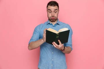 casual man looking through a book and blowing cheeks
