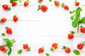 Delicious fresh strawberries and leaves of mint on white wooden background, top view. Flat lay, copy space. Ugly organic strawberry