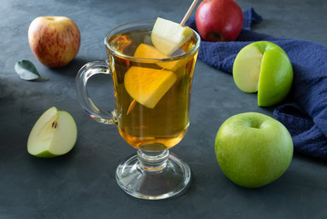 Apple juice in a glass and a few ripe apples on a dark grey-blue surface. Concept healthy eating, healthy lifestyle. Selective focus, horizontal orientation.