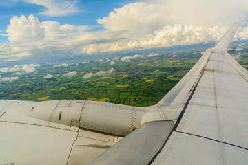 A plane wing with a landscape from Ireland at the background.