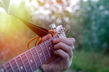 The hand of a young man holds a musical chord on an acoustic guitar