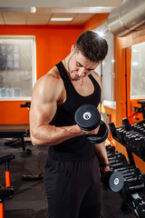 Strong, healthy young man lifting weights in the gym during a workout. Young teenage male with...