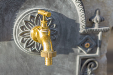 Fototapeta na wymiar brass water tap on stone wall background, blurred background