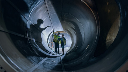 Two Heavy Industry Engineers Walking Inside Pipe, Use Laptop, Have Discussion, Checking Welding....