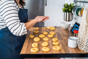 Woman preparing homemade donuts in her kitchen following a recipe online. Baking concept