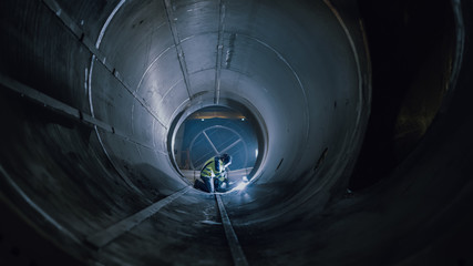 Professional Heavy Industry Worker Wearing Helmet Welding Inside Oil and Gas Pipe. Construction of...