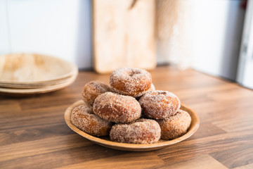 Close up of a tray of freshly baked homemade sugar donuts on a wooden table in a kitchen