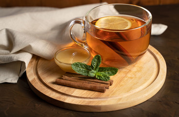 Transparent Cup with fragrant black tea, mint, cinnamon and honey on a natural background. Concept for your design, advertising.