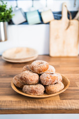 Close up of a tray of freshly baked homemade sugar donuts on a wooden table in a kitchen
