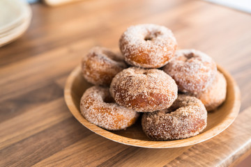 Close up of a tray of freshly baked homemade sugar donuts on a wooden table in a kitchen