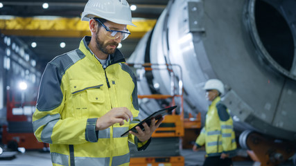 Heavy Industry Engineer Stands in Pipe Manufacturing Factory, Use Digital Tablet Computer. Facility...