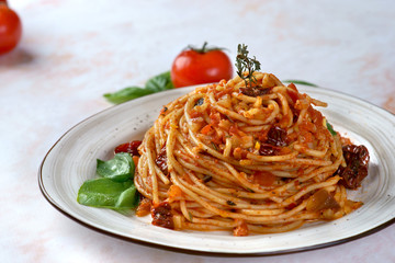 Pasta with tomato sauce, sun-dried tomatoes and olives on a light background