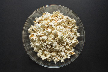 Popcorn close up in a clear glass Cup top view on a black background and copy space