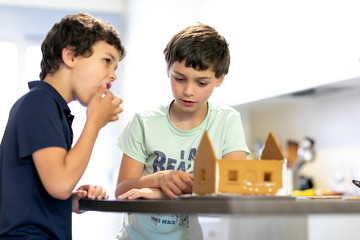 Two boys making a gingerbread house in the kitchen