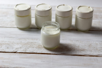 Home made yogurt in glass jars  on white wooden background