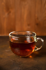Transparent Cup with fragrant black tea on a blackboard on a natural background. Concept for your design, advertising.