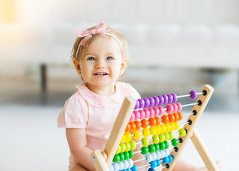 Adorable baby girl with educational toy scores in home or kindergarten