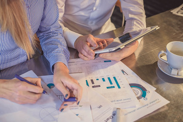 View of business people, sitting at the table and pointing handles on the chart and on tablet