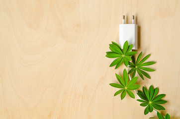 The concept energy save. white electric plug, cord, wire with green leaves on woode background. Eco friendly home. copy space, text