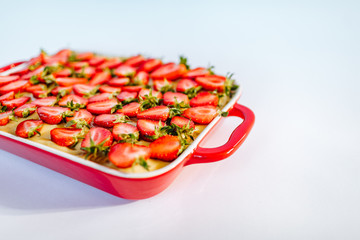 Strawberry pie in red ceramic baking dish on the white background