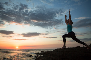 Fototapeta na wymiar Yoga woman doing exercises on the atlantic ocean coast at twilight. Porto, Portugal.