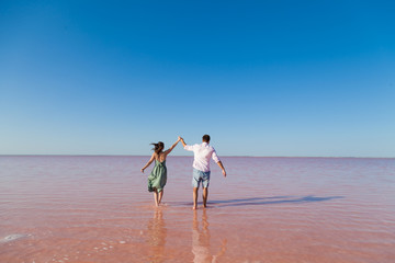 woman and man stand together in rose water lake against the blue sky