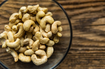 Cashew nuts in a small plate on a vintage wooden table as a background. Cashew nut is a healthy vegetarian protein nutritious food.